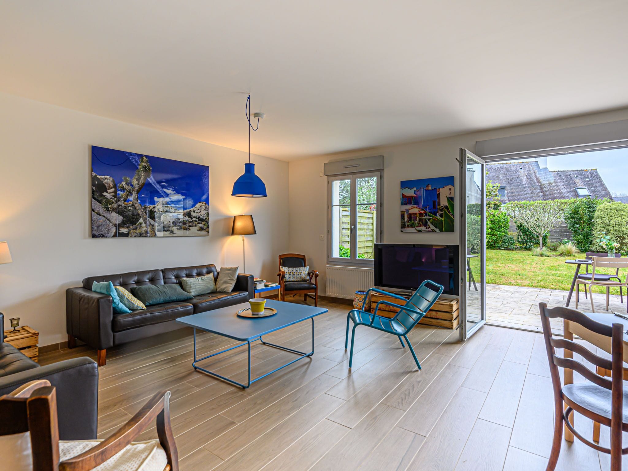 A modern living room with a sofa, coffee table, and chairs. There is a TV and artwork on the wall.