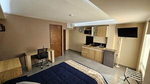 A compact hotel room with a bed, a desk, a kitchenette, and a TV. - A10 SUPER SUITE PREMIUM AT PLAZA ACEQUIA (Cuautitlan Izcalli)