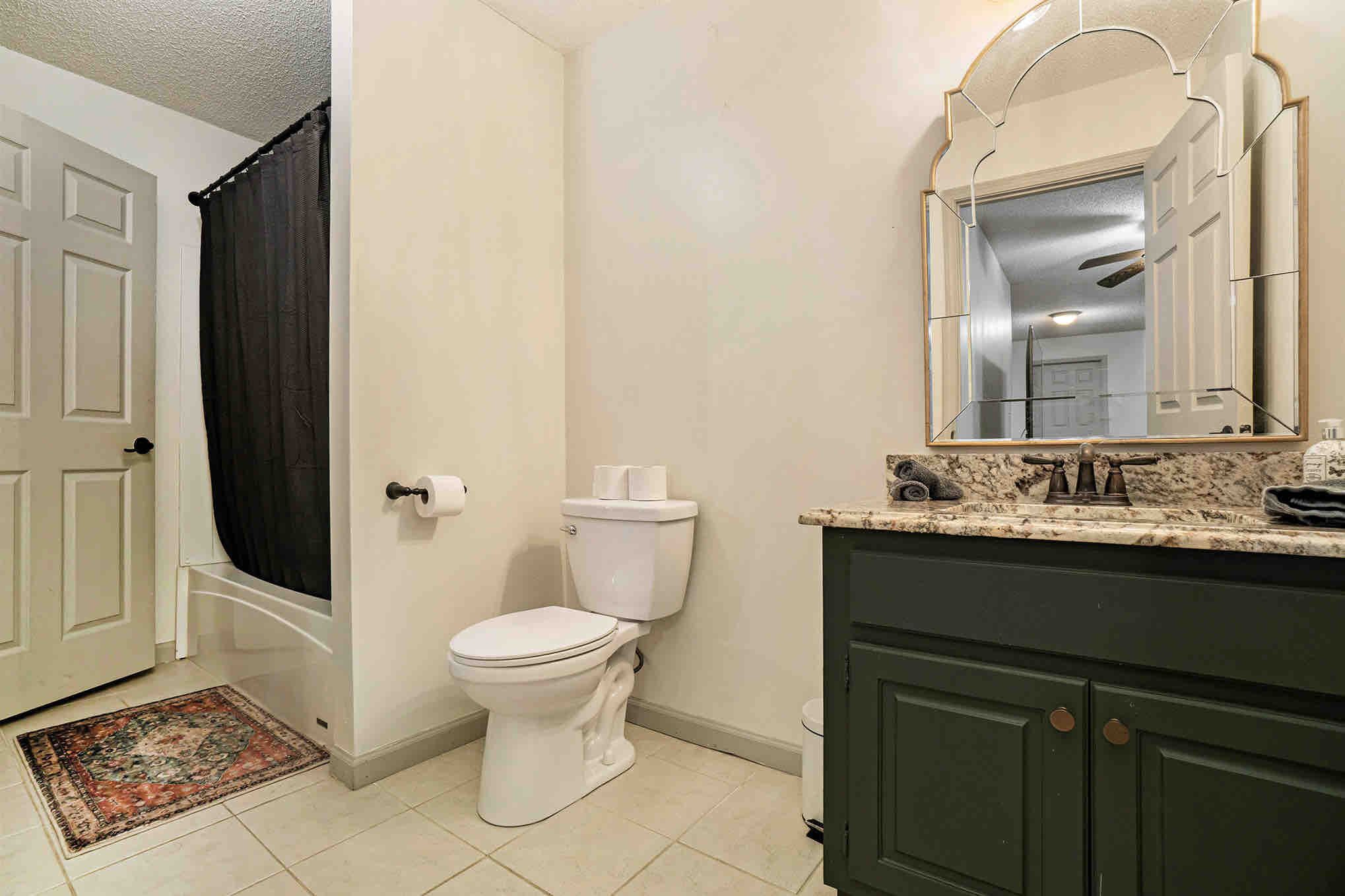 Een badkamer met toilet, wastafel, spiegel en douchegordijn.