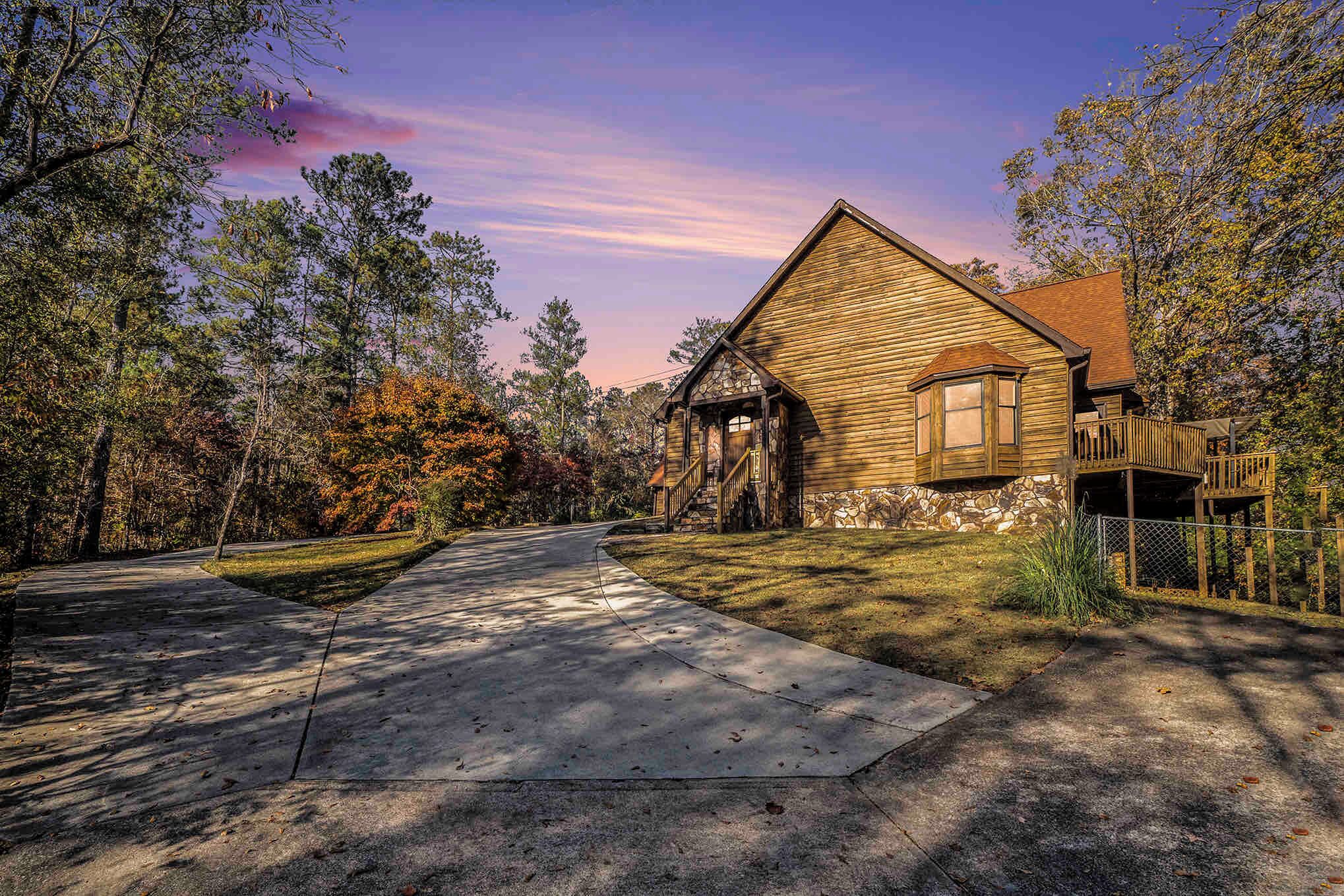 A wooden cabin with a stone foundation, a covered porch, and a fenced deck.