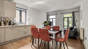 Une cuisine moderne avec un coin repas, comprenant une grande fenêtre, une table à manger avec quatre chaises et une plante en pot.