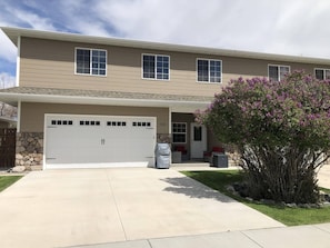 A two-story house with a garage, a stone wall, and a well-maintained lawn.
