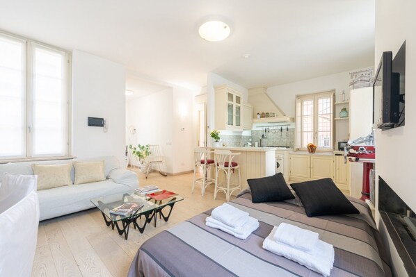 Un appartement moderne comprenant un espace de vie, une kitchenette et un lit.