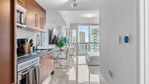 A modern kitchen with stainless steel appliances, wooden cabinets, and a large window overlooking a cityscape. - Studio in Miami/Brickell Business District-ICON Residences (Miami)