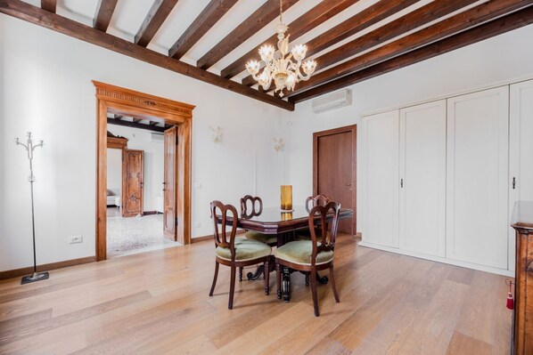 A dining area with a wooden table and chairs, a chandelier, and a white cabinet.