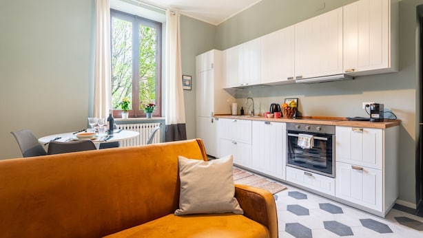 A modern kitchen with white cabinets, a dining area with a table and chairs, and a sofa with a cushion. - Comfortable apartment located on the second floor, of four in total, of a 1930/40s building with no elevator.In 75 square meters of space it comfortably accommodates four people with one bedroom with a double bed and one bedroom with two single beds.It i (Parma)