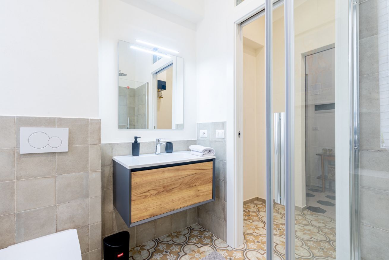Een moderne badkamer met een houten wastafelmeubel, een spiegel en een douchehoek.