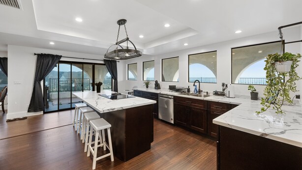 A modern kitchen with a large island, dark wood cabinets, and a view to the outside. - Beautiful Fallbrook Estate Ideal for Weddings and Events (Fallbrook)