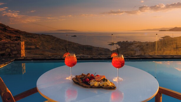 A poolside table with a fruit platter and two drinks, overlooking a scenic view of the sea and hills. - Private 1-Bedroom Villa Suite in Mandrakia with Swimming Pool (Mandrakia)