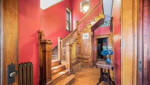 A wooden staircase with a red wall and a radiator on the left.