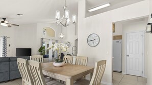 Un comedor con una mesa y sillas de madera, una lámpara de araña y un reloj en la pared.