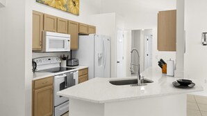 Una cocina moderna con electrodomésticos blancos, armarios de madera y una isla grande con fregadero.