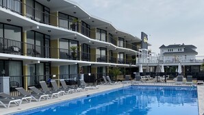 A hotel with a swimming pool, multiple balconies, and outdoor seating areas. - Poolside Condo - Just 2 blocks from the Beach, Boardwalk and Seaport Pier!  (North Wildwood)