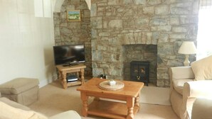 A living room with a stone fireplace, a television on a wooden stand, and a sofa.