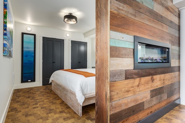 Une chambre à coucher avec un lit, un mur décoratif en bois, un téléviseur et un tableau accroché au mur.