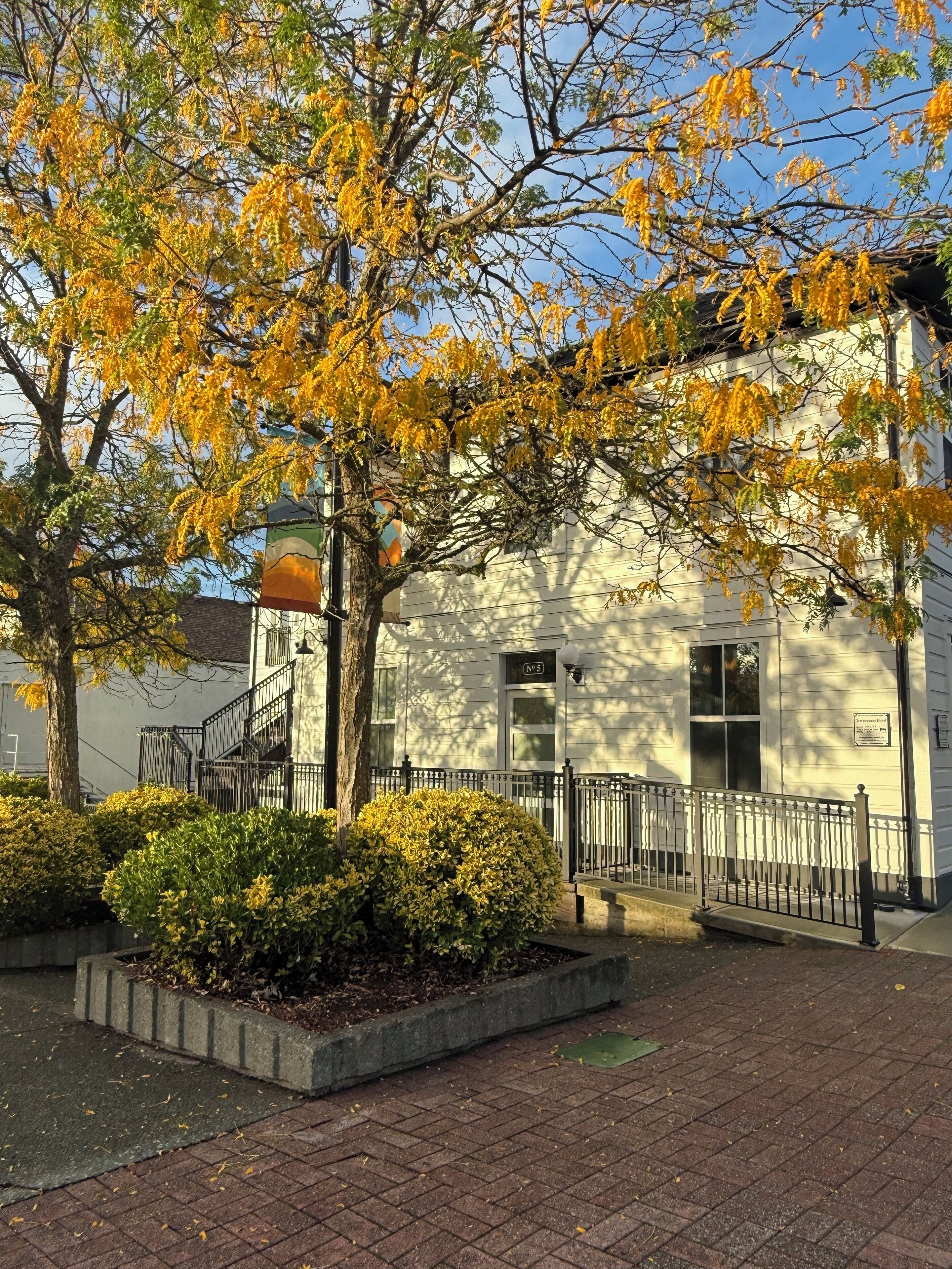 A building with a white exterior, a black metal fence, and a staircase leading to the entrance.