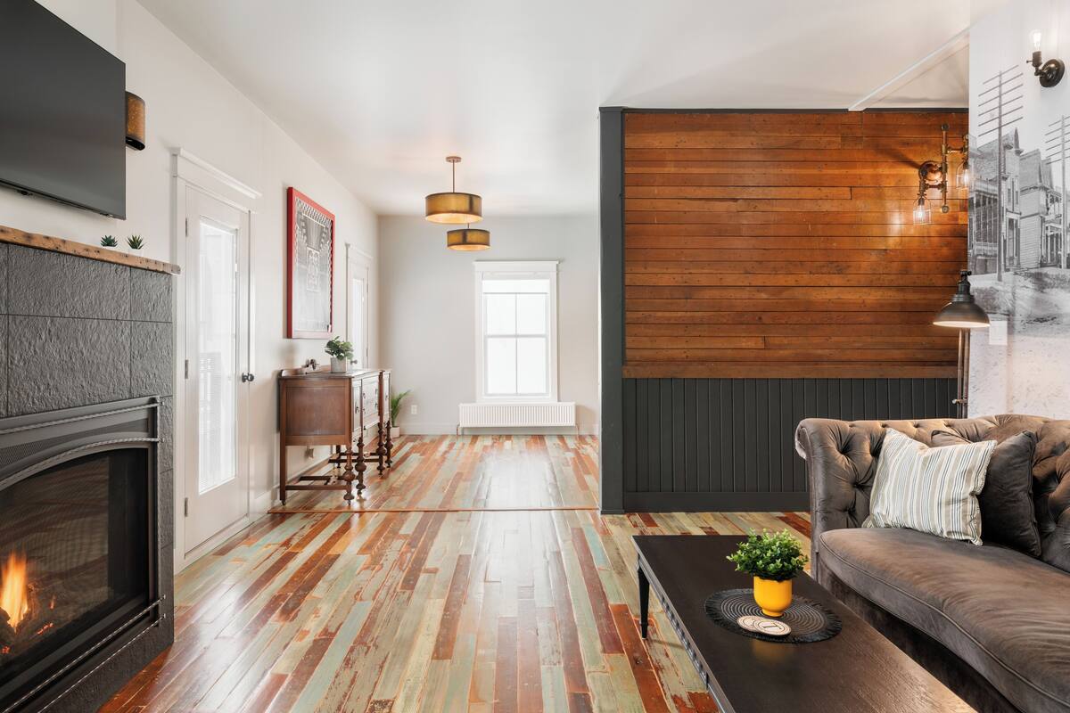 A living room with a fireplace, wooden flooring, a sofa, and a coffee table.