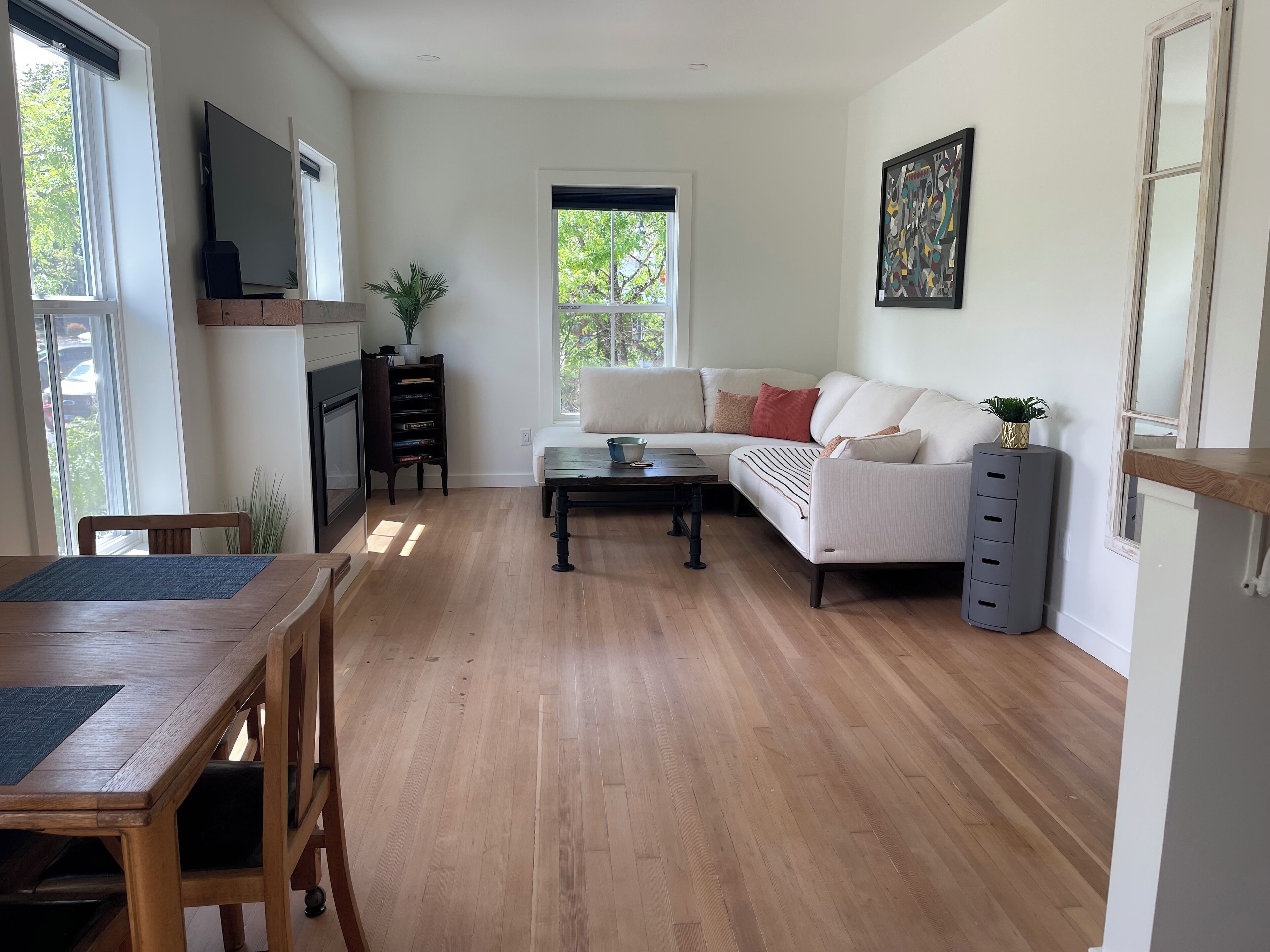 Un salón amplio con suelo de madera, un sofá blanco, una mesa de centro y una chimenea.