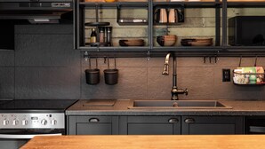 A modern kitchen with a stainless steel range hood, a double sink, and a wooden backsplash. - Temperance Hotel (Ladysmith)