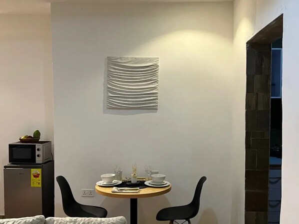 Enjoy a meal for two at the compact room's small table, complete with a microwave and refrigerator nearby.