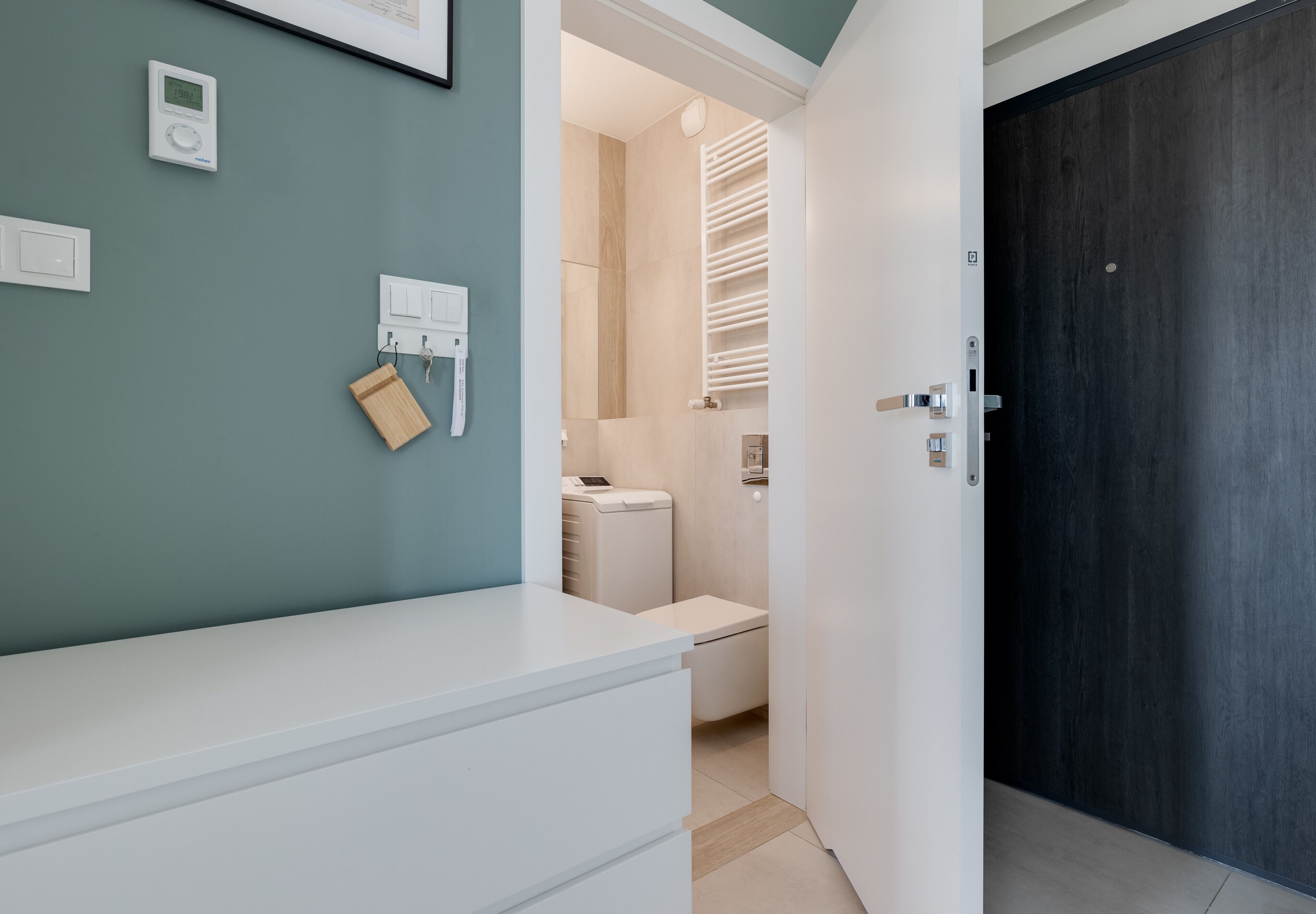 Ein modernes Badezimmer mit einem weißen Waschtisch, einem Handtuchhalter und einer Toilette.