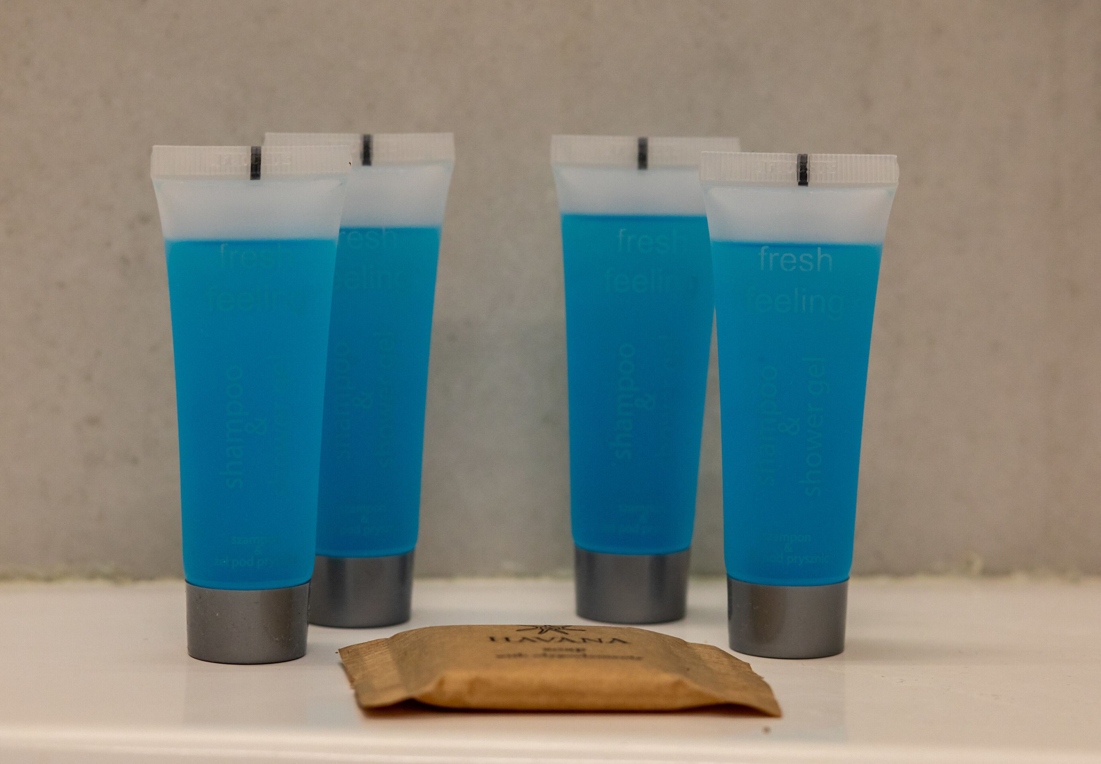 Four tubes of blue liquid with white caps and gray bases, and a small brown packet on a white surface.
