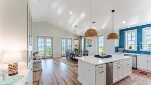 A spacious kitchen with a large island, white cabinetry, and a blue-tiled backsplash. - The Dune Buggie is an elegant, custom built 3BD/3BA home w/gulf views from every angle! (Port Saint Joe)