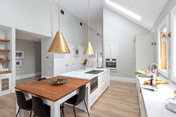 A modern kitchen with a central island, pendant lights, and a view of the adjacent dining area.