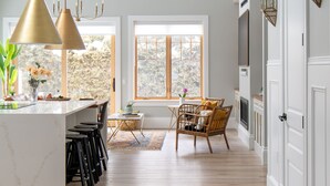 A modern kitchen with a central island, pendant lights, and a view through large windows. - The Haven on Halton (Perth)