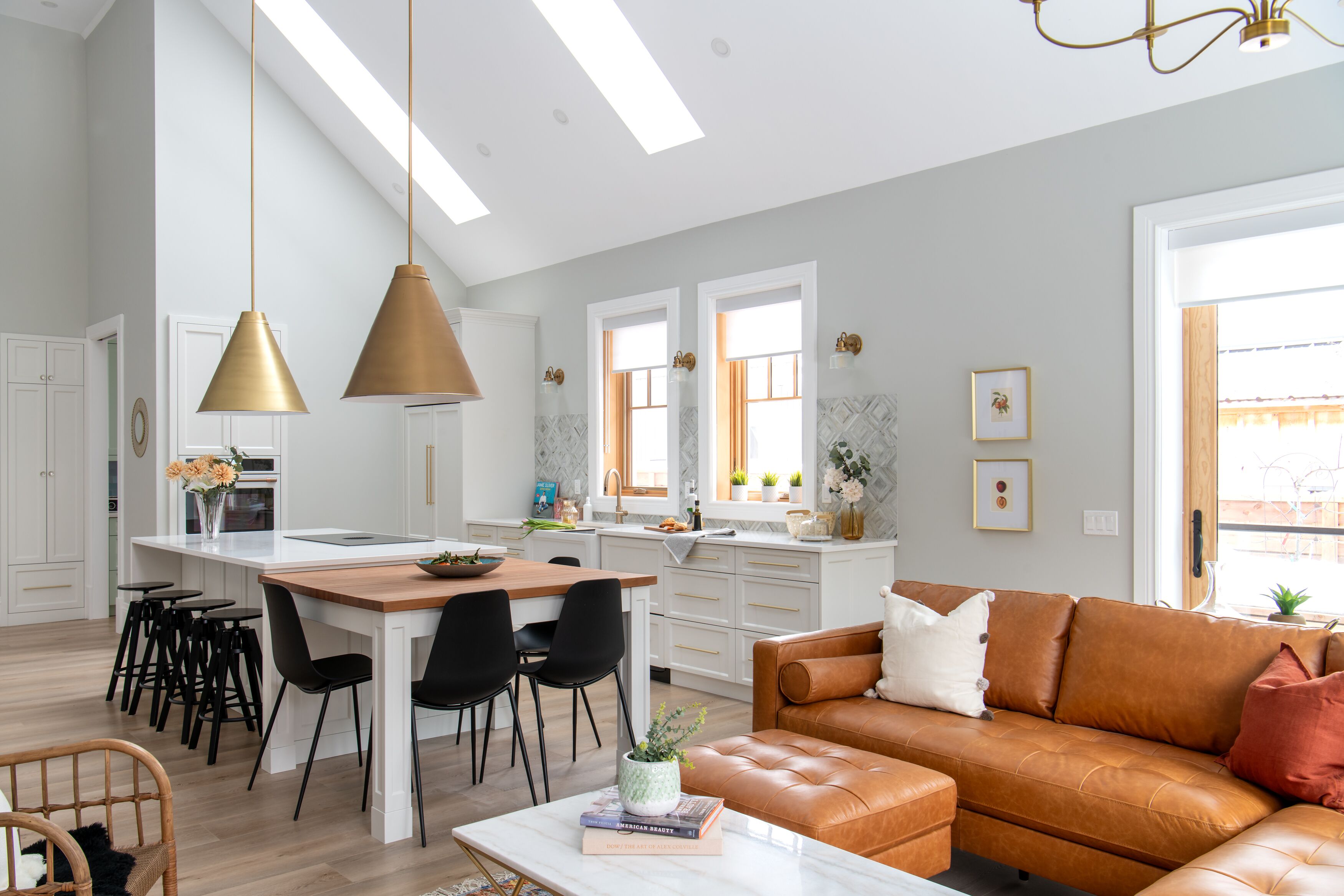 Une cuisine moderne avec des meubles blancs, un îlot central en bois et des tabourets de bar noirs.