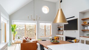 A modern kitchen with a large island, a dining area with a sofa, and a fireplace. - The Haven on Halton (Perth)