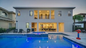 Une maison à deux étages dotée d’une piscine, d’un espace extérieur aménagé et d’un intérieur bien éclairé.