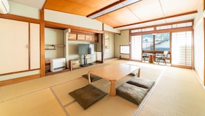 A traditional Japanese room with tatami flooring, a low table, cushions, sliding doors, and a view of the outside. - Kinosaki Onsen Yuyado Sasakura (Toyooka)