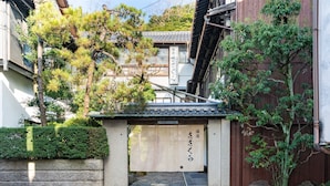 A traditional Japanese building with a wooden entrance, stone steps, and a sign with Japanese characters. - Kinosaki Onsen Yuyado Sasakura (Toyooka)