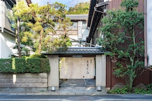Un edificio japonés tradicional con entrada de madera, escalones de piedra y un letrero con caracteres japoneses.