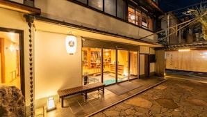 A traditional Japanese building with a stone patio, a wooden bench, and a visible interior with tatami mats. - Kinosaki Onsen Yuyado Sasakura (Toyooka)