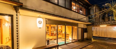 A traditional Japanese building with a stone patio, a wooden bench, and a visible interior with tatami mats.