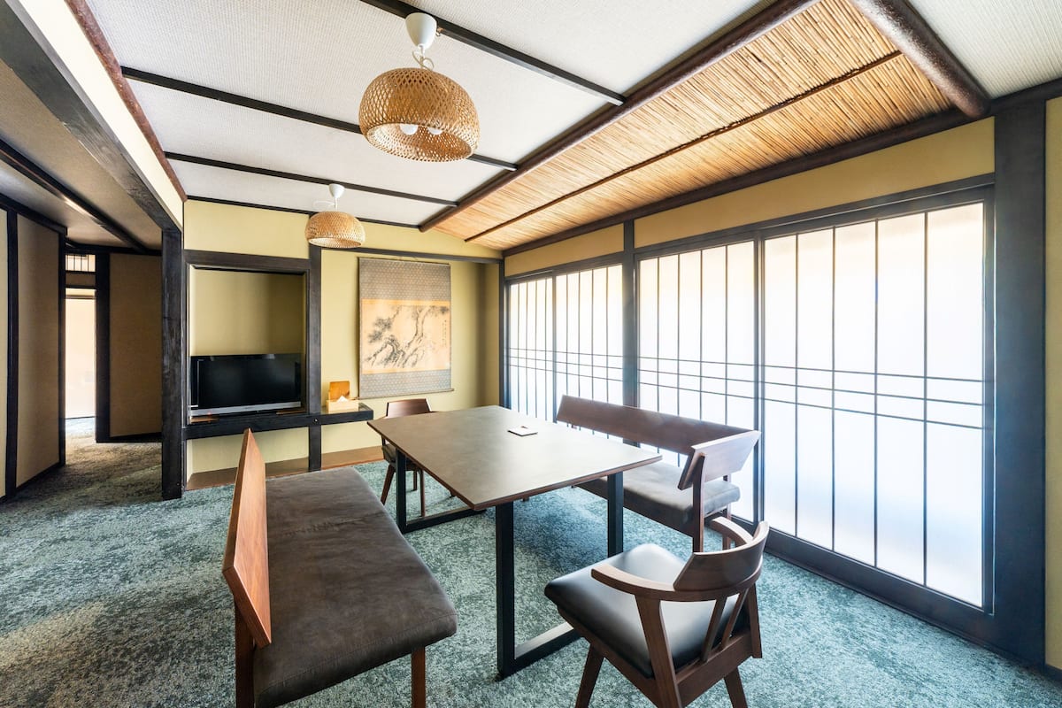 Una habitación japonesa tradicional con suelo de tatami, una mesa baja y puertas correderas.
