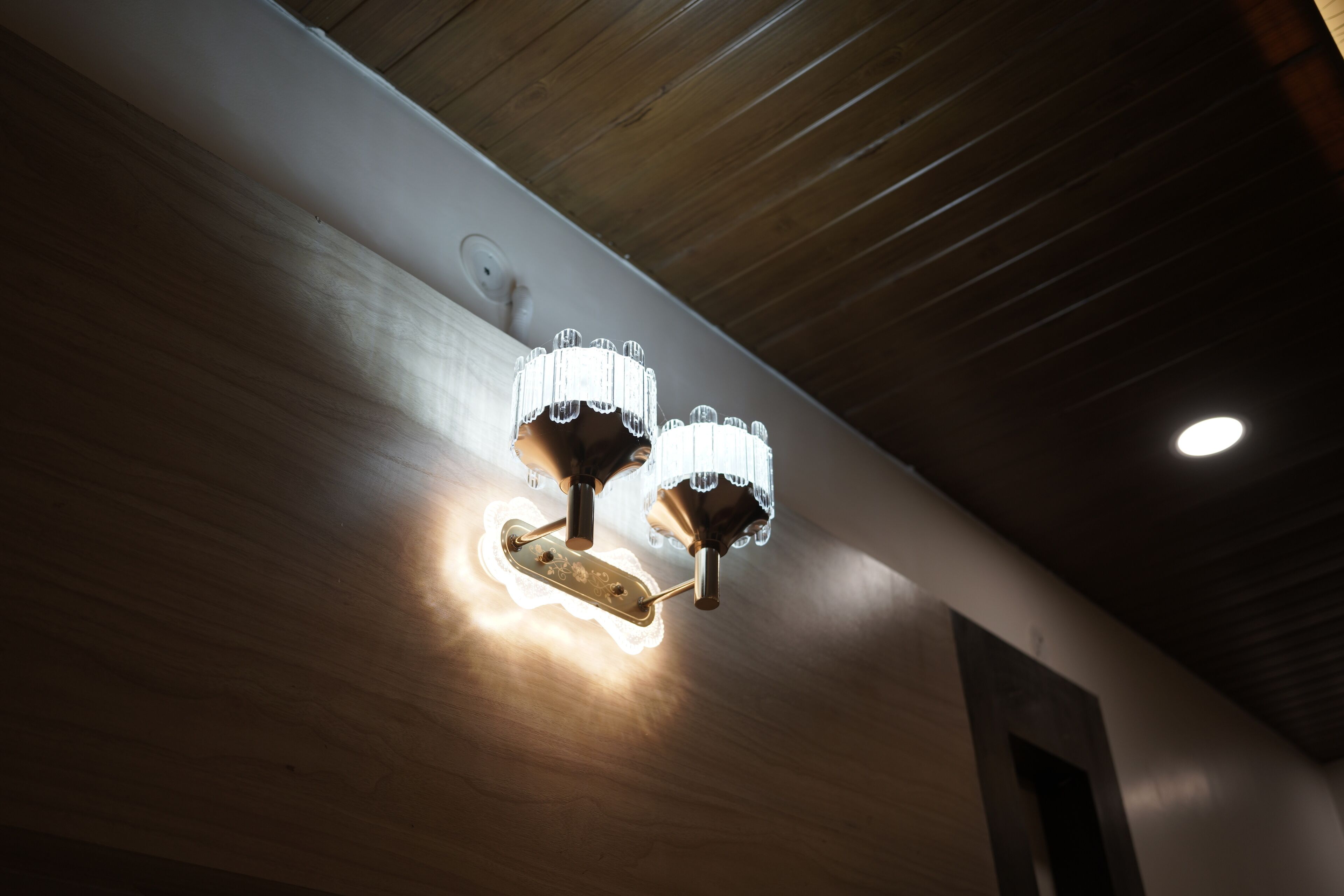Ein modernes Interieur mit Holzbalkendecke und einer wandmontierten Leuchte.
