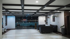 Un hall d’entrée spacieux avec un plafond haut, un éclairage moderne et un coin salon avec des canapés.