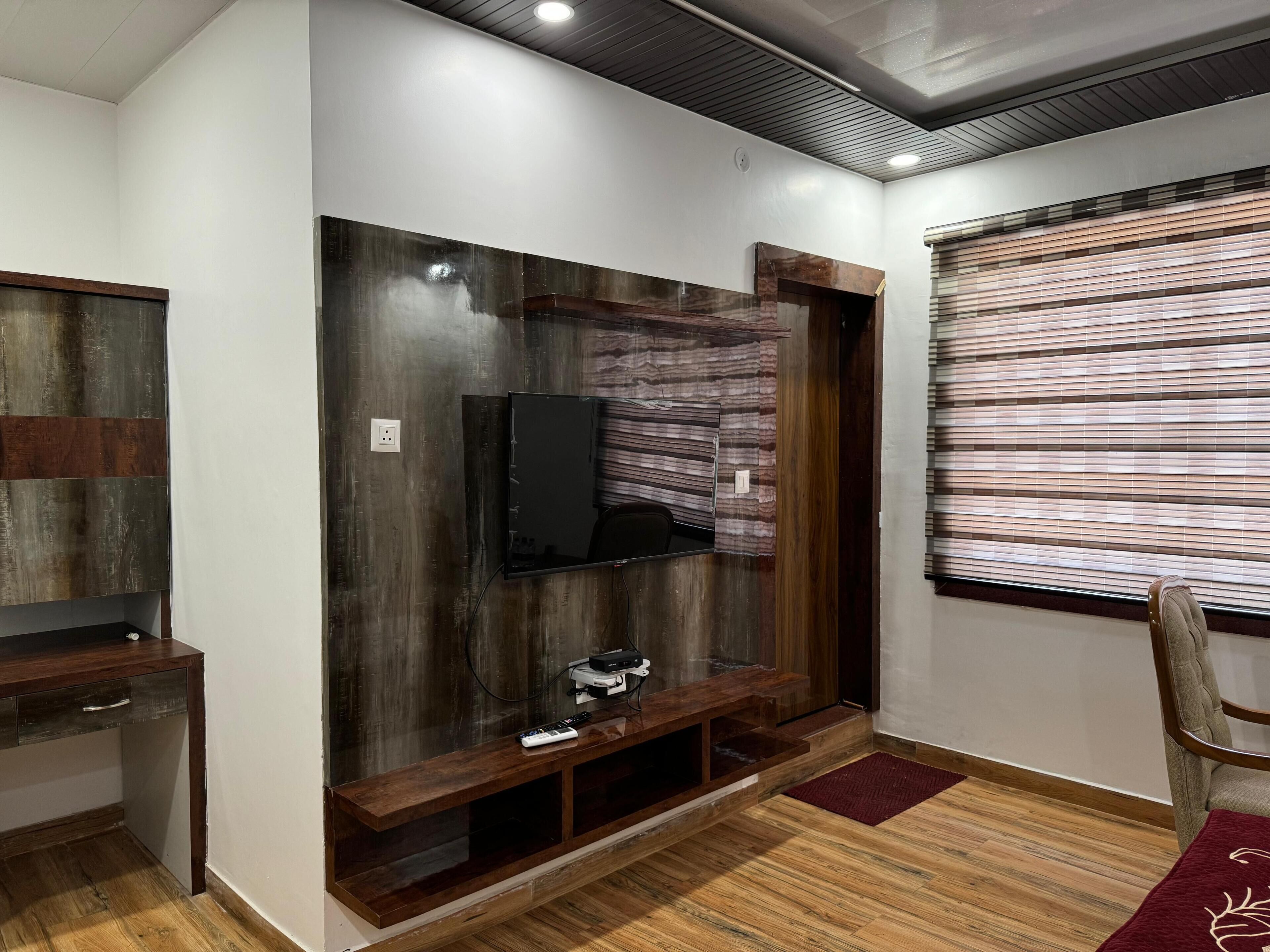 Un salon moderne doté d’un téléviseur encastré, d’un meuble de rangement en bois et d’une fenêtre avec des stores.