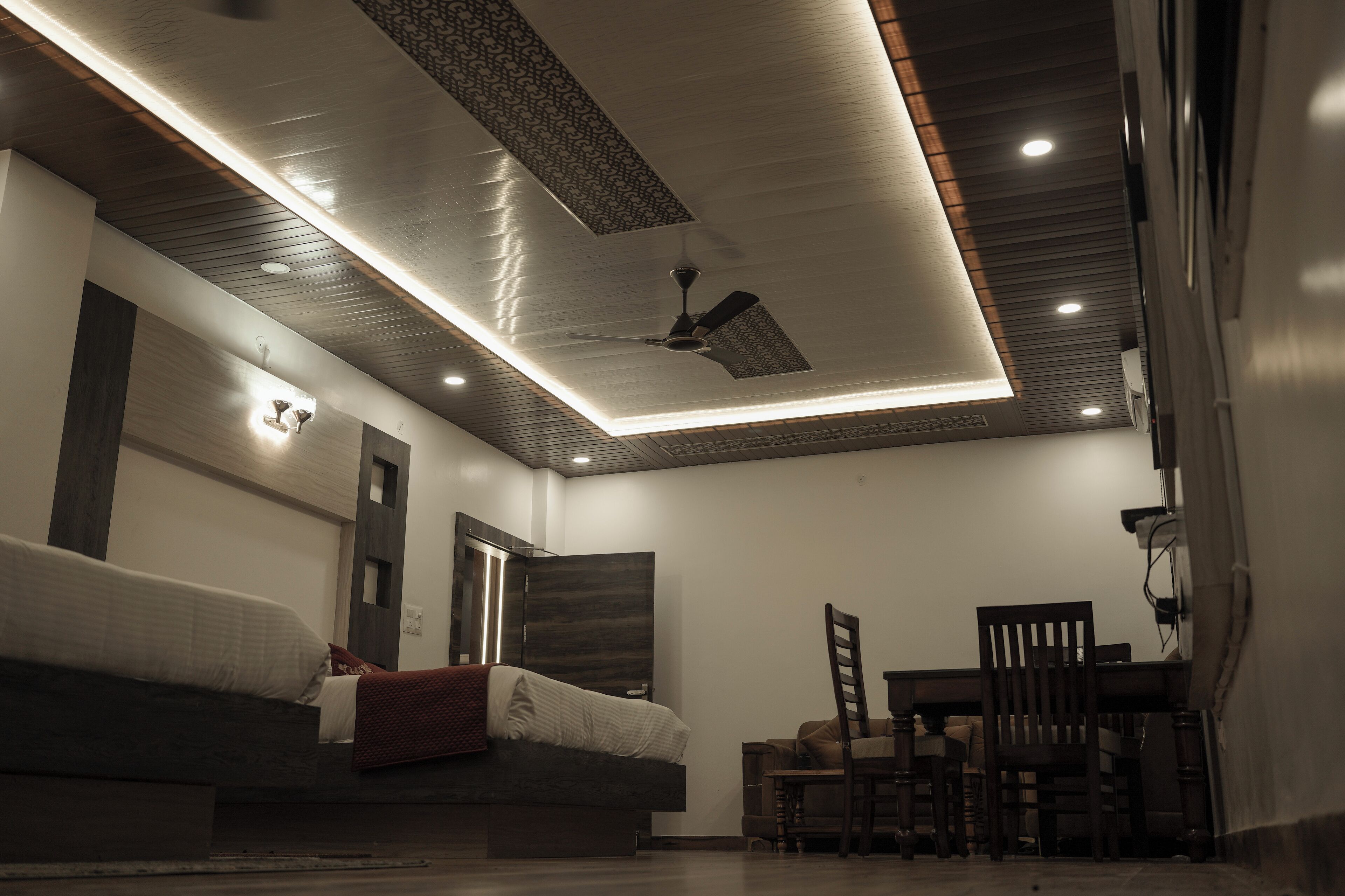 Un dormitorio moderno con cama, ventilador de techo y un comedor con sillas y mesa.