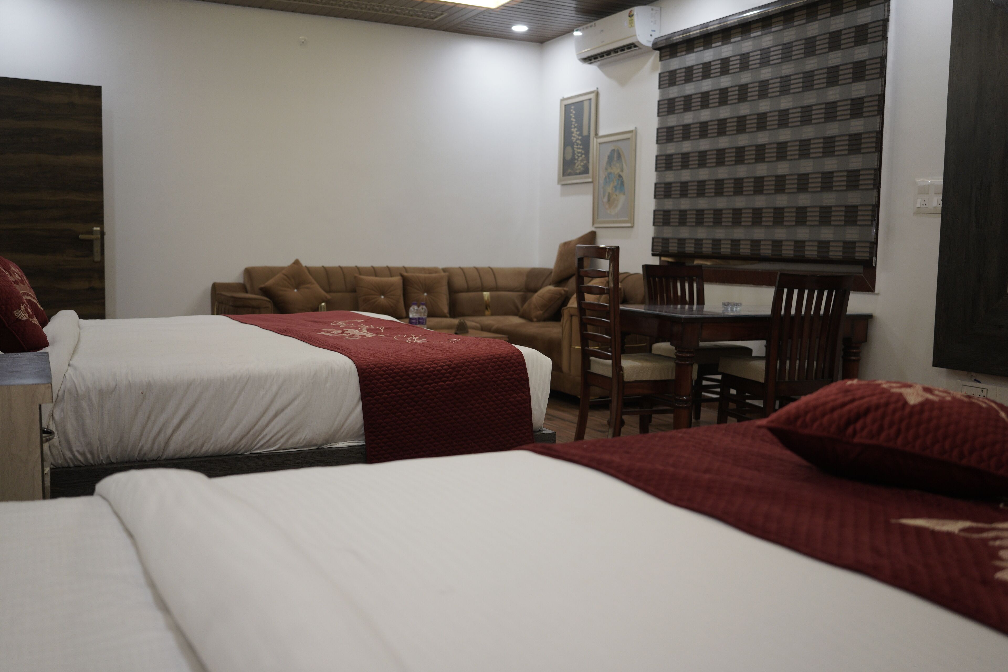 Une chambre d’hôtel avec deux lits, un canapé, une table à manger avec des chaises et un téléviseur.