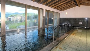 Piscina interna com janelas amplas, teto de madeira e piso revestido.
