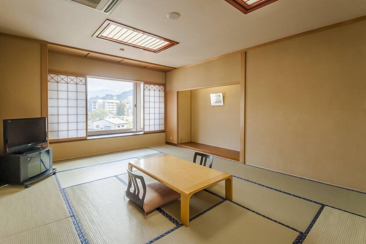 Ein traditioneller japanischer Raum mit Tatami-Bodenbelag, einem niedrigen Tisch und einem Fernseher.