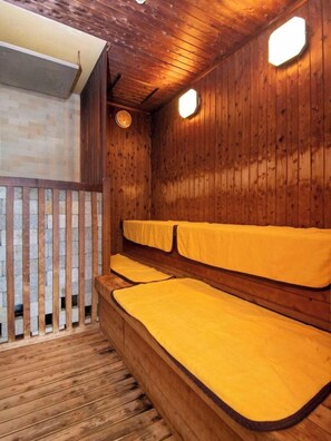A wooden cabin with a wooden floor, a wooden bench, and a bed with yellow bedding. - KKR Yuzawa Yukiguni (Yuzawa)