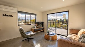 Una sala moderna con un sillón gris, un sofá marrón, un televisor y una mesa de centro de madera.