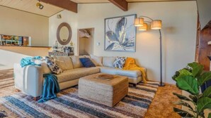 Ein Wohnzimmer mit einer Couch, einem Hocker und einer Stehlampe.