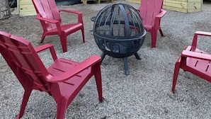 A black building with a white door and windows, surrounded by red chairs and a fire pit. - Private Riverfront, Converted Barn *EV Charger* (Princeton)