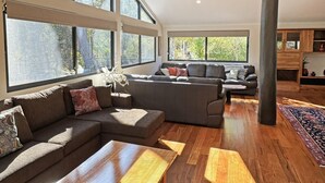 A spacious living room with large windows, a sectional sofa, and a wooden coffee table. - Springdale Gums: Denmark Forest Retreat (Hay)